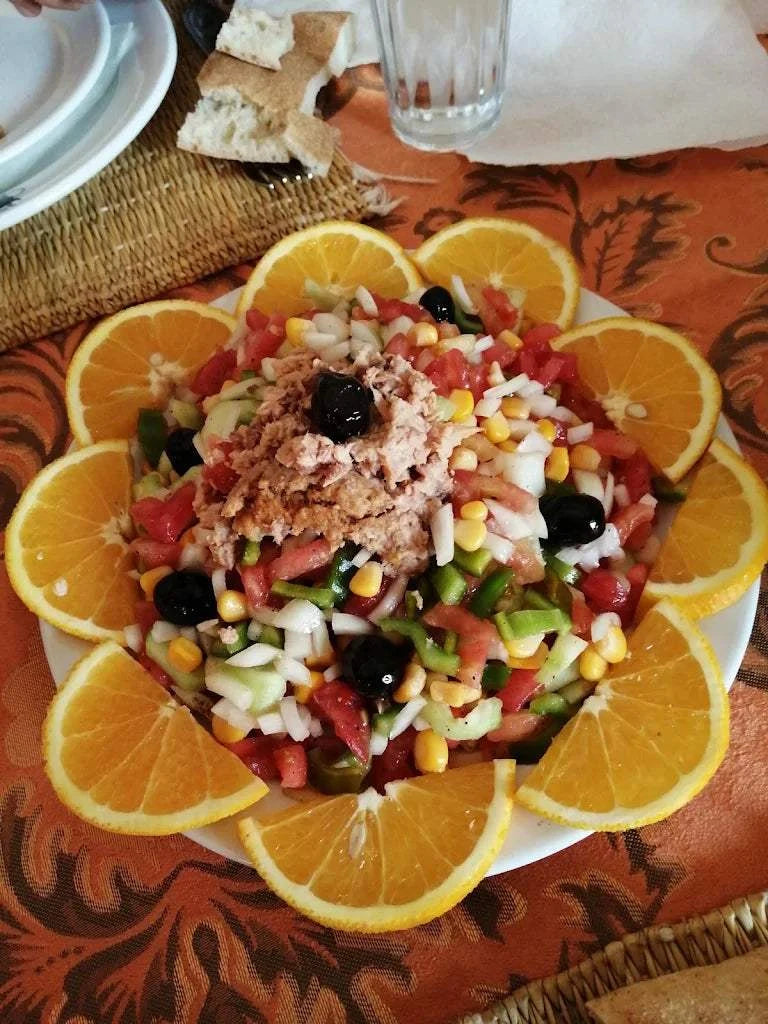 Hotel auberge Sahara colorful fresh vegetable salad with corn, tomatoes, onions, black olives, and tuna, garnished with orange slices
