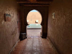 Hotel auberge Sahara courtyard with traditional Moroccan stucco archway, terracotta tiles with circular patterns, and a pool