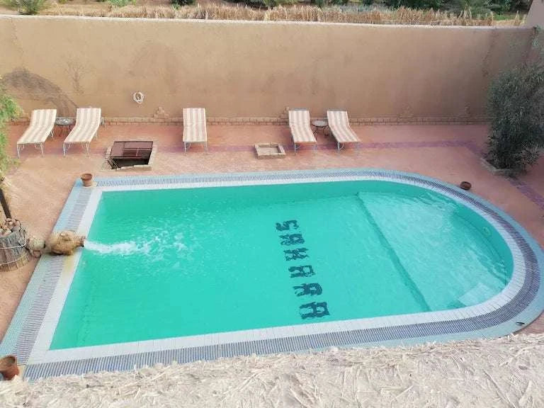 Hotel auberge Sahara outdoor rectangular swimming pool with chamfered corners and water spout in turquoise water