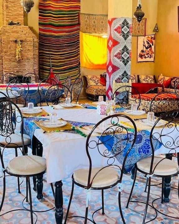 Hotel Camping Les Roses indoor dining area with wrought iron chairs, patterned tablecloths, and vibrant textiles