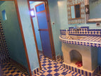 Hotel Kasbah Ksar Bicha bathroom with blue and white geometric tiled sink and floor, wooden doors, and blue textured walls