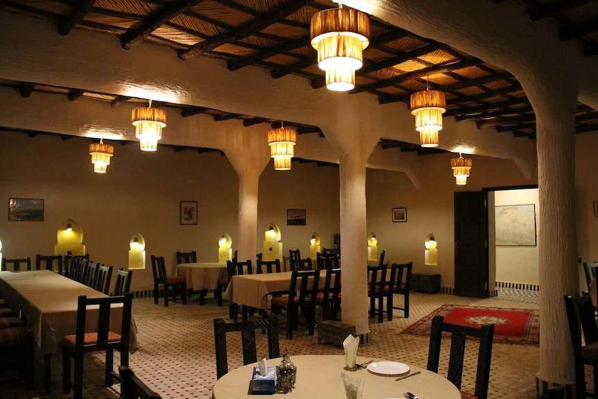 Hotel Kasbah Ksar Bicha interior with warm lighting, wooden ceiling, beige walls, and traditional carpeted floor