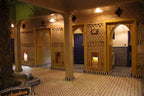 Hotel Kasbah Ksar Bicha traditional Moroccan kasbah-style architecture interior with yellow and brown adobe walls, arches, columns, and tiled black and white patterned floor