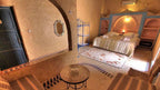Hotel Kasbah Ksar Bicha bedroom with Moroccan style decor featuring a double bed, patterned rug, archway, and textured walls