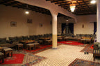 Hotel Kasbah Ksar Bicha spacious traditional Moroccan lounge with patterned cushions, striped benches, red and patterned carpets