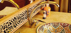 Hotel Ksar Merzouga ceramic sink with intricate yellow and brown geometric patterns and a polished chrome faucet in a marble countertop