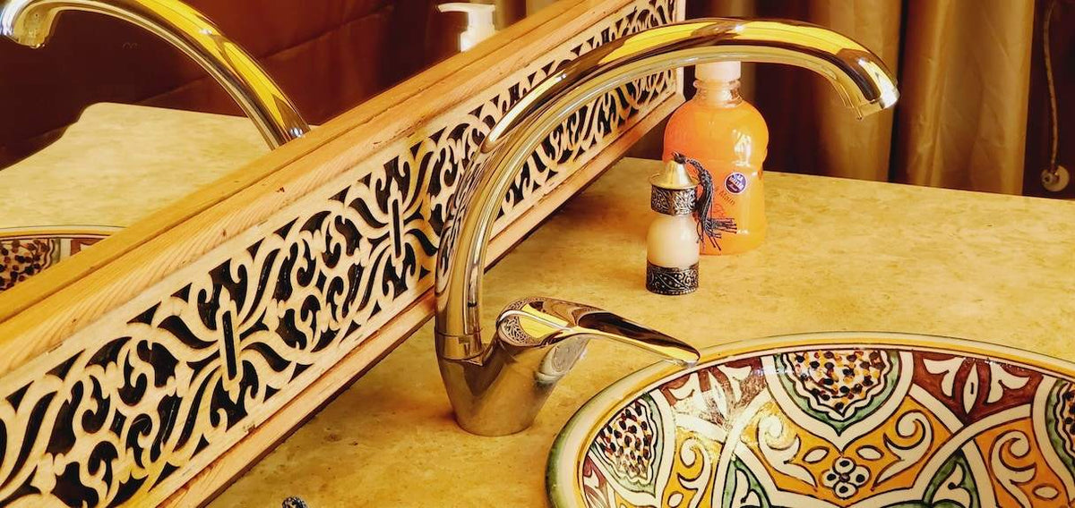 Hotel Ksar Merzouga ceramic sink with intricate yellow and brown geometric patterns and a polished chrome faucet in a marble countertop