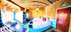 Hotel Ksar Merzouga room with twin beds, bright turquoise and yellow tiled floor, patterned cushions, and rustic yellow walls