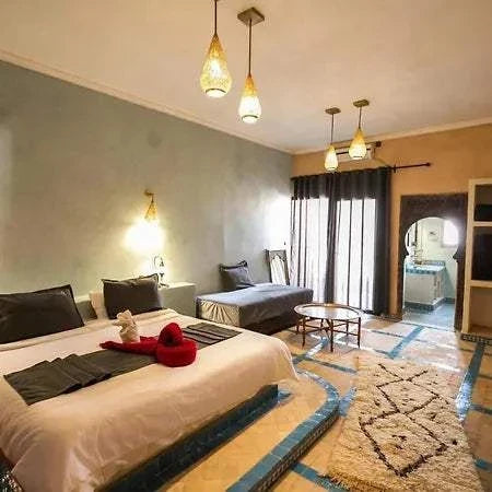 Hotel Nomad Palace bedroom with light blue and sandstone walls, twin and single beds, Moroccan patterned rugs, and hanging pendant lights