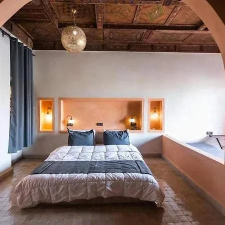 Hotel Nomad Palace bedroom with terracotta-colored walls, wooden ceiling, gray curtains, and double bed with gray and white bedding