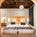 Hotel Nomad Palace bedroom with two twin beds, white bedding, gray pillows and throws, Moroccan style lighting and warm-toned wall accents