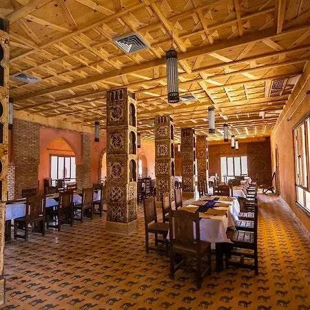 Hotel Nomad Palace Moroccan desert restaurant with wooden ceiling, patterned tiled floor, decorated pillars, and traditional style chairs