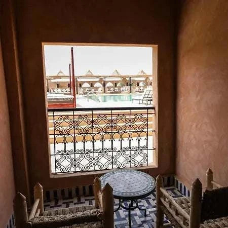 Hotel Nomad Palace room balcony with rustic wooden chairs, mosaic tiled floor, and pool view through decorative railing