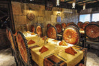 Hotel Xaluca Dades dining area with ornate wooden chairs featuring red and orange patterns, yellow tablecloths, and folded orange napkins