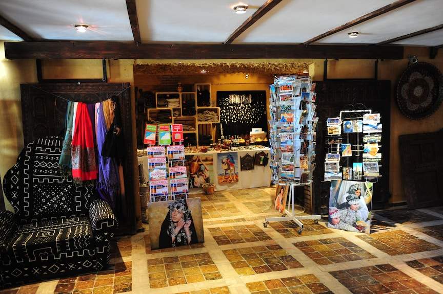Hotel Xaluca Dades gift shop interior with colorful scarves, postcards, traditional Moroccan crafts, and decorative textiles