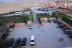 Hotel Xaluca Dades parking area with various vehicles including vans and cars in a paved lot surrounded by greenery and desert landscape