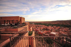 Hotel Xaluca Dades rooftop terrace with wrought iron railings overlooking a vast desert town and landscape at sunset