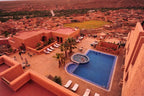 Hotel Xaluca Dades featuring terracotta buildings, outdoor swimming pool with Jacuzzi, palm trees, and lounge chairs