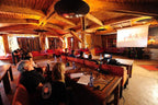 Hotel Xaluca Dades meeting room with warm wooden interiors, red cushioned seating, and Moroccan patterned wall hangings