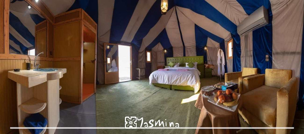 Hotel Yasmina Merzouga luxury tent room with green carpet, olive green bed, beige armchairs, blue and white striped tent interior