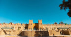 Hotel Yasmina Merzouga exterior featuring traditional Moroccan architecture in sandy beige with decorative patterns and multiple national flags