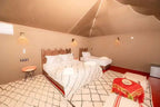 Kal Tenere Agafay luxury desert camp bedroom with two beds, beige walls, wooden headboards, patterned rugs, and warm lighting