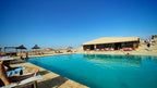 Kal Tenere Agafay luxury desert camp with a large blue outdoor swimming pool, sun loungers, stone deck, and clear blue sky