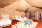 Kal Tenere Agafay luxury desert camp interior with beige canvas walls and ceiling, double and single beds, patterned cushions, and cozy rugs