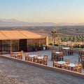 Kal Tenere Agafay outdoor seating area with wooden tables and chairs on a desert terrace overlooking distant mountains and arid landscape