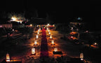 Kalimba Luxury Desert Camp at night with lit Moroccan lanterns lining a red carpet pathway in the sandy desert