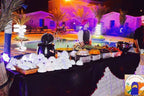 Kasbah Hotel Bar outdoor buffet setup at night with illuminated palm trees, stacked white bowls, and a server in traditional attire
