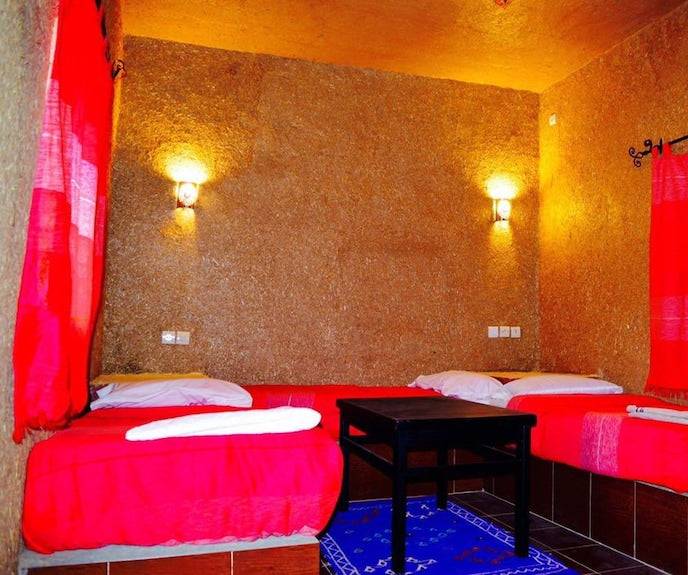 Kasbah Hotel Bar seating area with vibrant red cushions and curtains, textured brown walls, and soft wall sconces lighting