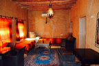 Kasbah Hotel Bar with warm orange decor, traditional Moroccan rug, wicker chairs, and wood-beamed ceiling