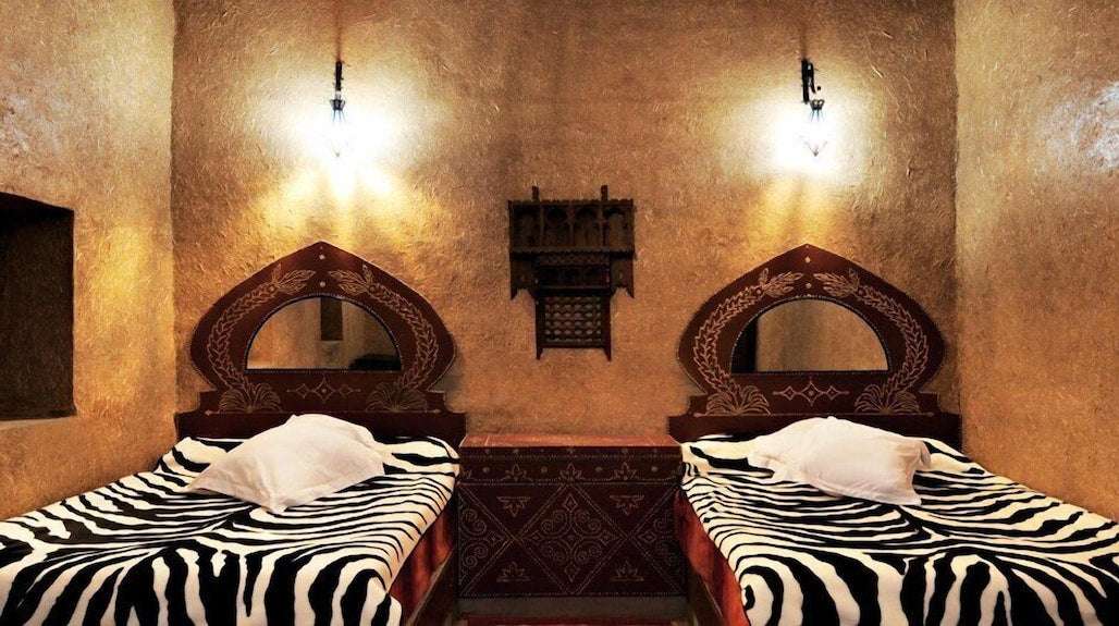 Kasbah Hotel Bar room with traditional Moroccan earthy walls, wooden headboards, and zebra pattern bed covers