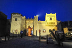 Kasbah Hotel Tombouctou warm yellow facade with traditional Moroccan architecture and soft evening lighting under a deep blue sky