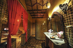 Kasbah Hotel Xaluca Moroccan style bathroom with mosaic tiled walls and floor, wooden framed mirror, and red curtains