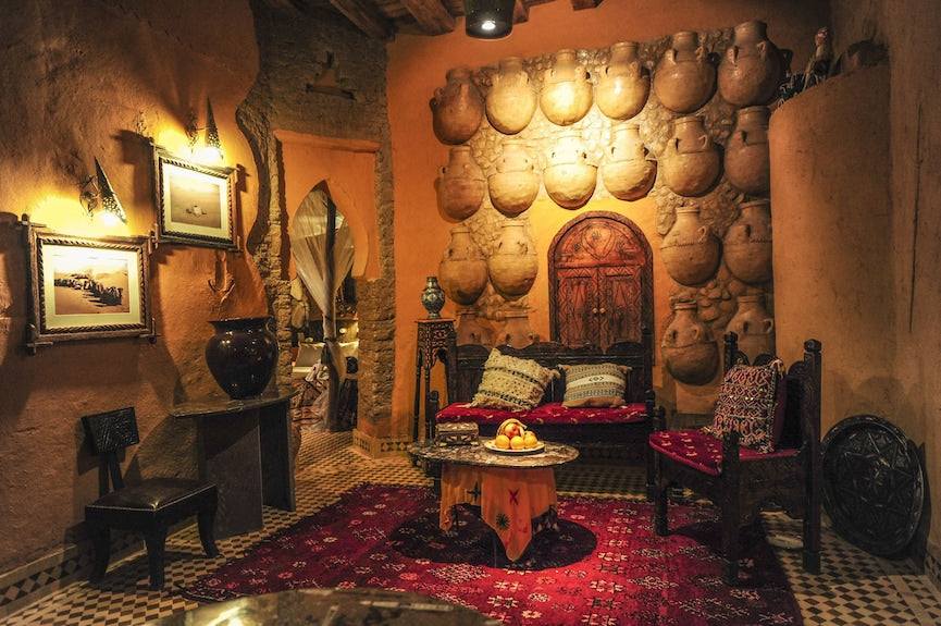 Kasbah Hotel Xaluca cozy rustic sitting area with traditional Moroccan clay pots wall decor warm earth tones and red patterned carpet
