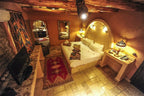 Kasbah Hotel Xaluca rustic room with adobe walls, wooden beams, patterned textiles, ambient lighting, and tiled floor