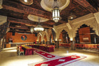 Kasbah Hotel Xaluca conference room with traditional Moroccan wooden ceiling, ornate arches, red and gold chairs, and red carpet