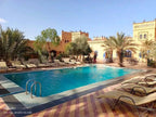 Kasbah Le Touareg outdoor swimming pool with turquoise water, surrounded by beige loungers, palm trees, and traditional Moroccan architecture