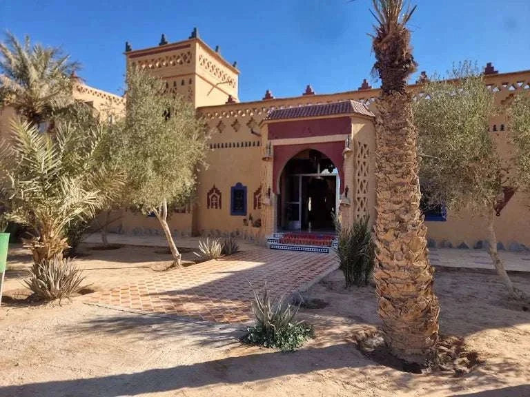 Kasbah Le Touareg traditional Moroccan mud brick building with crenellated towers, decorated facade, and palm trees