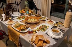 Kasbah Le Touareg traditional Moroccan dining table set with assorted dishes, bread, and decorative tablecloth in warm tones