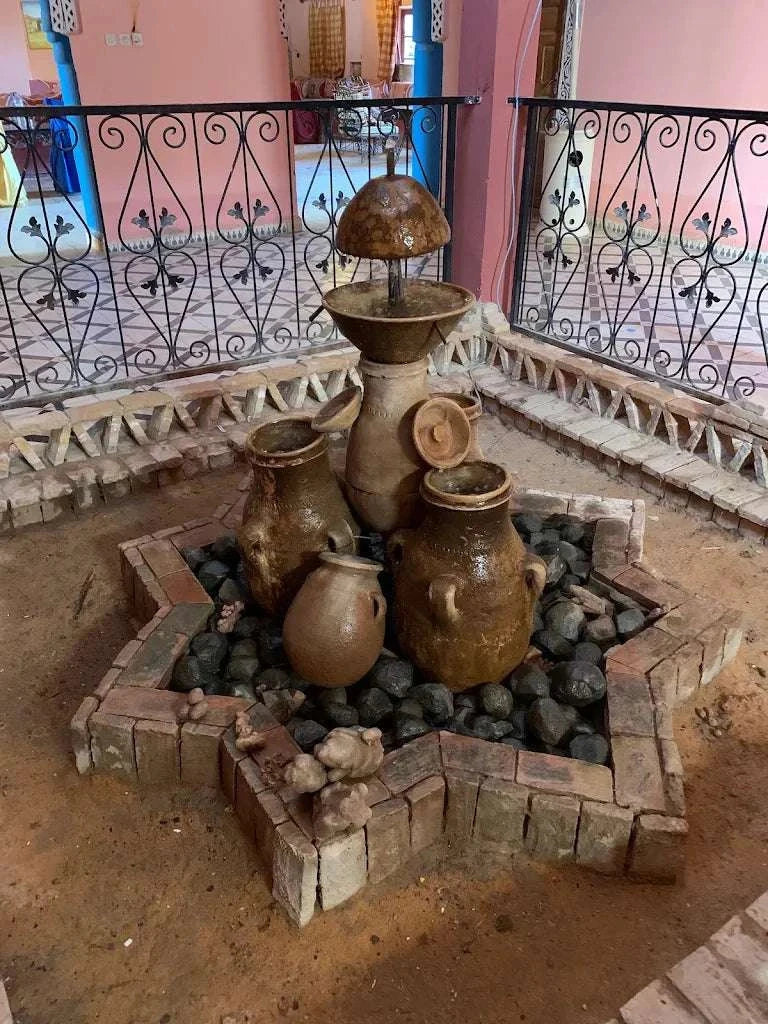 Kasbah Le Touareg traditional brown ceramic pots arranged decoratively around a central stone feature inside a tiled courtyard with ornate metal railings