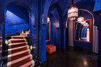 La Mamounia Marrakech interior featuring deep blue walls with Moroccan arches, red and white striped carpet on stairs, and hanging lanterns