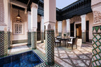 La Mamounia Marrakech indoor courtyard with white and green tiled columns, marble patterned floor, and dining table with chairs