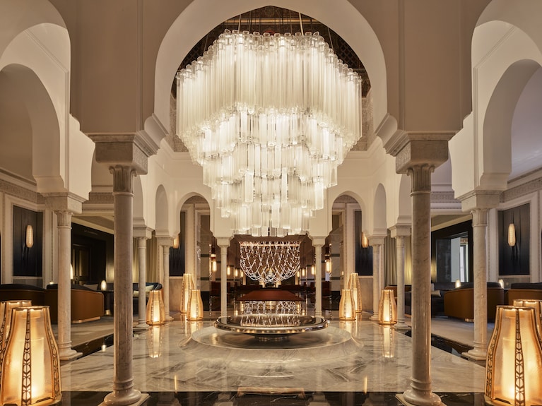 La Mamounia Marrakech elegant lobby with grand crystal chandeliers, marble floors, arched columns, and ambient lighting