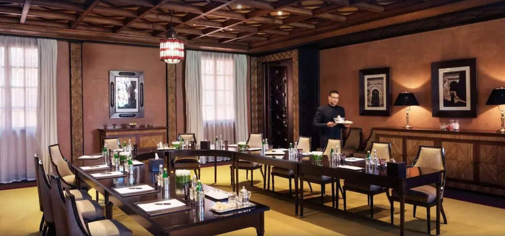 La Mamounia Marrakech elegant meeting room with traditional Moroccan design wooden ceiling, beige chairs, and dark wood tables