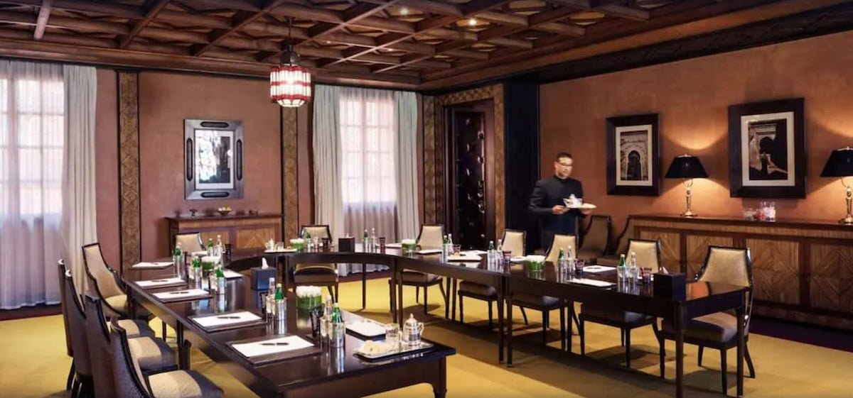 La Mamounia Marrakech elegant meeting room with traditional Moroccan design wooden ceiling, beige chairs, and dark wood tables