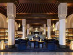 Elegant lounge area in La Mamounia Marrakech with navy blue velvet seating, ornate pillars, wooden ceiling, and warm lighting