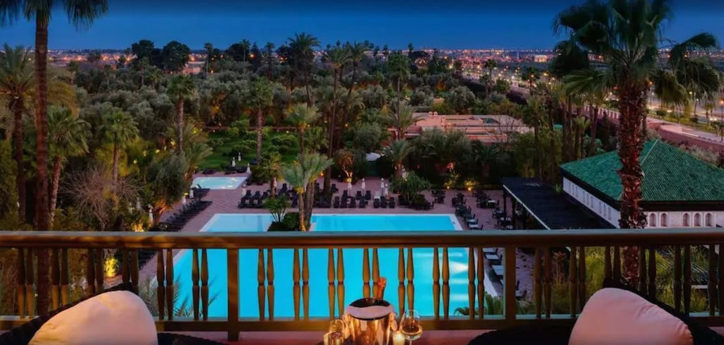 La Mamounia Marrakech view of illuminated outdoor pool area with surrounding palm trees and city lights at dusk